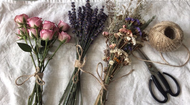 Blumenbündel hängen kopfüber unter alten Holzbalken in einer rustikalen Scheune