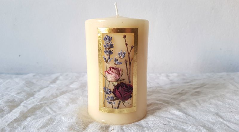 Elegant gestaltete Kerze mit Gold-Wachsplatten-Rahmen und botanischem Arrangement aus Rosen und Lavendel
