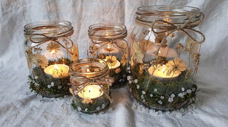 Fertige Windlichter in verschiedenen Naturmaterial-Varianten, stimmungsvoll bei Kerzenschein arrangiert