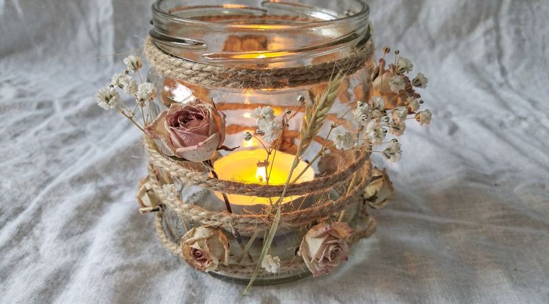 Fertiges Windlicht mit Trockenblumen, von innen beleuchtet, warmes Abendlicht