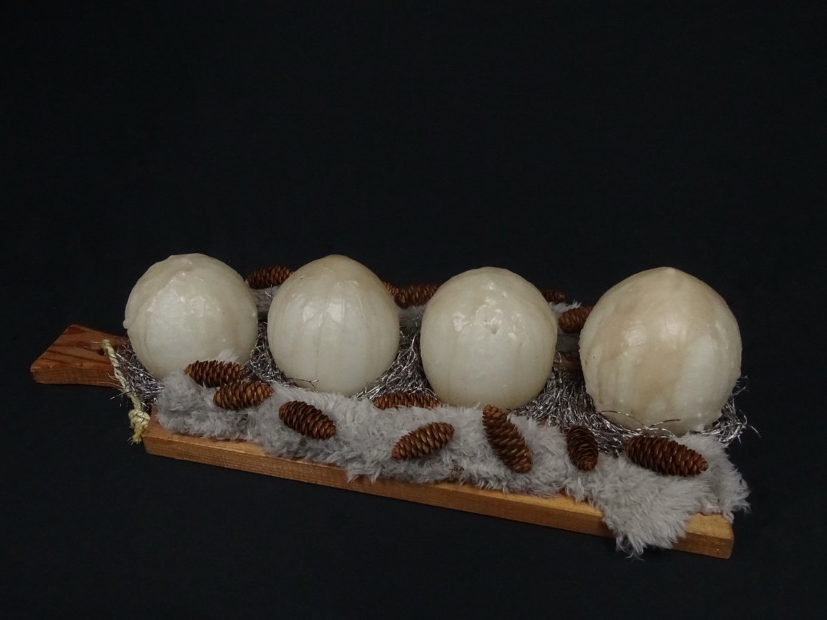 Adventsgesteck mit vier Kugelkerzen auf Holzbrett