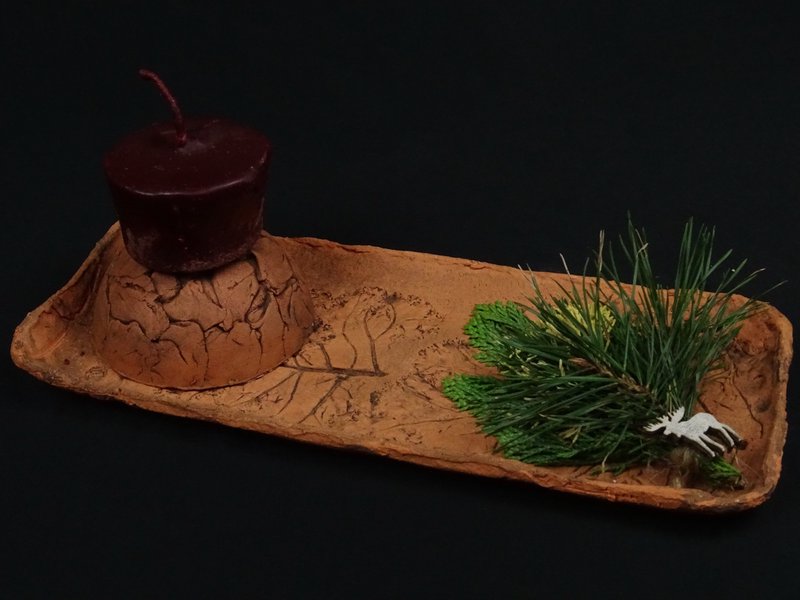 Länglicher Tonteller mit dunkelroter Kerze und Elch