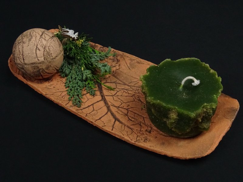 Tonteller mit Tonkugel und grüner Kerze