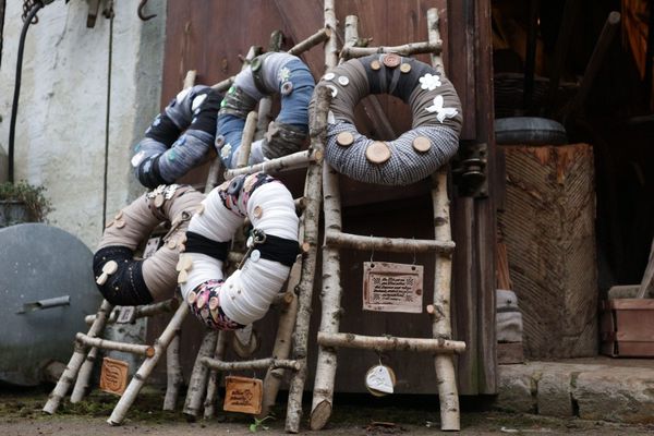 Handgemachte Stoffkränze mit Holzknöpfen und Birkenscheiben auf einer Birkenleiter in der Scheune