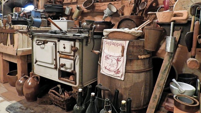 Historische Küchenecke in der Scheune mit antikem Ofen, Holzfass und alten Flaschen